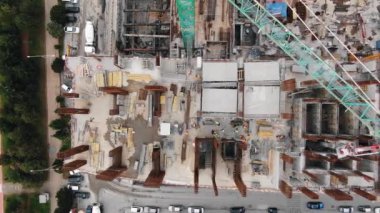 Otoyollar arasındaki inşaat alanında uçuş. İşçilerin ve inşaat vinçlerinin yukarıdan görünüşü. İşçiler beton döker ve kaynak demiri döker.
