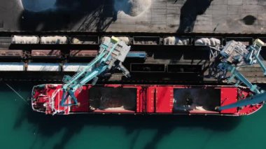 Büyük liman vinçleri limandaki bir deniz gemisinden hava manzaralı vagonlara ezilmiş taş ya da gübre taşır. Uluslararası deniz ve küresel ticaret taşımacılığı.