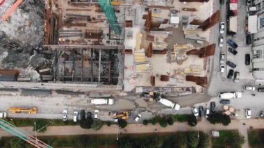 İnşaat alanındaki bir vincin havadan görüntüsü. Çelik yelekli işçiler beton dökerler. Monolitik güçlendirilmiş beton yapının inşası