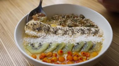Süper yiyeceklerle dolu canlı bir kahvaltı kasesi: kivi, muz, tohum ve hindistan cevizi taneleri güne lezzetli ve sağlıklı bir başlangıç sunar. Superfood Kahvaltı Kabı. Bir kaşık lezzetli bir şey kapar