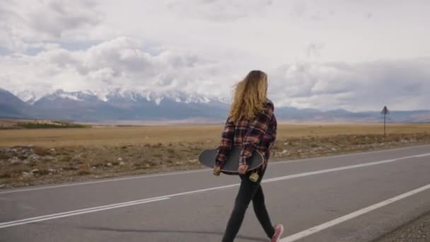 Kobieta Trzymająca Deskorolkę Wyrusza Podróż Spacerując Otwartą Autostradą Kierunku Odległych — Wideo stockowe