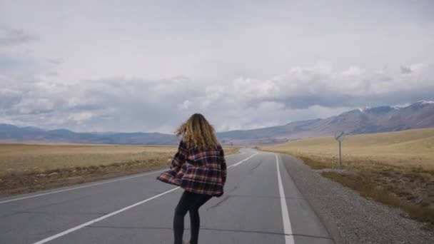 Young Woman Skateboards Empty Road Arms Outstretched Facing Expanse Wild — Stock Video