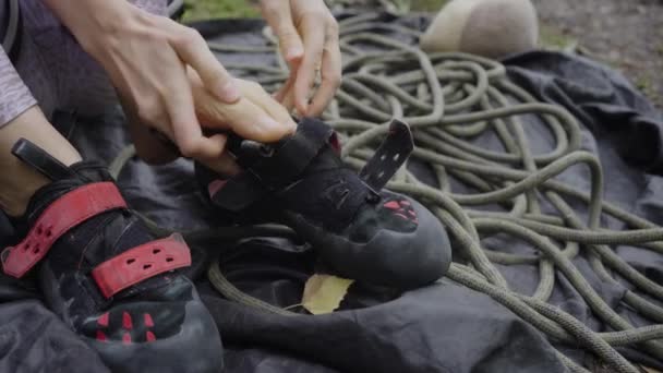 一名登山者的特写镜头 她的手适合专门的登山鞋 重点是在带绳索的帆布上进行详细的调整 一位攀岩者正准备爬上悬崖 — 图库视频影像
