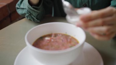 Kadın elleri usulca bir kase geleneksel pancar çorbasına bir tutam ekşi krema ekliyor. Taze yemek hazırlama ve süslemeyi vurguluyor. Bir kadın çorba kasesinde ekşi krema karıştırıyor..