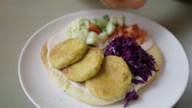 Kadınların elleri taze falafel pirzolalarına limon suyu sıkıyor sebzeler ve humuslarla dolu bir çukurda, lezzetli ve sağlıklı bir Vagan yemeği..