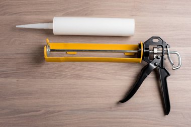 white silicone sealant cartridge and yellow-black sealant gun
