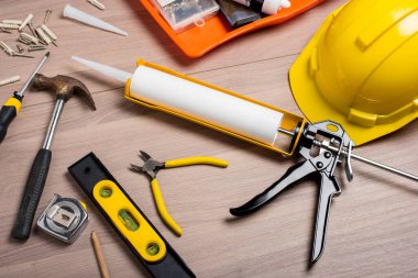 closeup white silicone sealant cartridge and yellow-black sealant gun