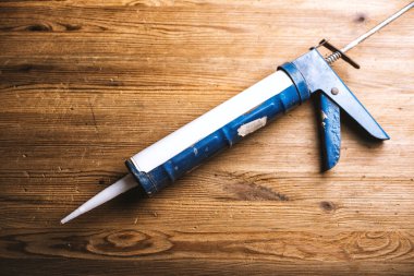 white silicone sealant cartridge and blue sealant gun