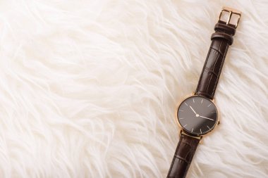 Woman wristwatch with black dial and brown leather bracelet.
