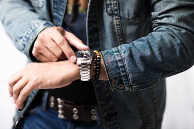 closeup luxury men watch with black dial and stainless steel bracelet on wrist of man.