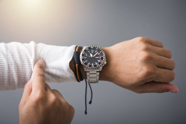 closeup luxury men watch with black dial and stainless steel bracelet on wrist of man.