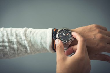 closeup luxury men watch with black dial and stainless steel bracelet on wrist of man.