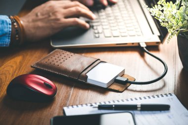 Closeup external hard drive on wooden desktop. Working with external hard drive.