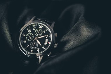 Closeup at luxury men wristwatch with black dial and leather strap.
