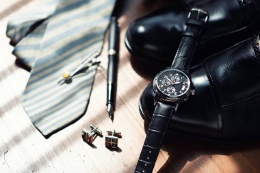Closeup at luxury men wristwatch with black dial and leather strap. Men wristwatch on the wooden desktop.