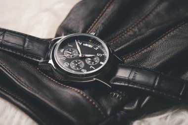 Men accessories on white background. Closeup at luxury men watch with black dial and leather strap.
