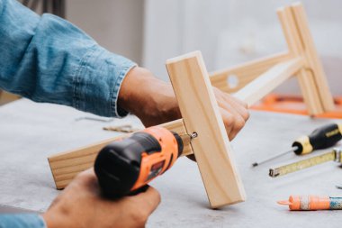 Siyah turuncu kablosuz tornavidayla çalışan adam. İnşaat ve DIY için elektrikli araç.