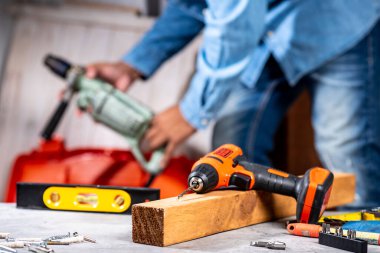 Siyah turuncu kablosuz tornavidayla çalışan adam. İnşaat ve DIY için elektrikli araç.