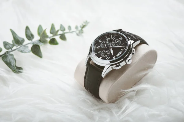 Men accessories on white background. Closeup at luxury men watch with black dial and leather strap.