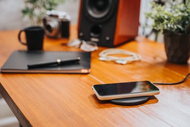 Akıllı telefonu masaüstünde kablosuz şarj cihazıyla şarj etmek.