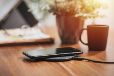 Akıllı telefonu masaüstünde kablosuz şarj cihazıyla şarj etmek.