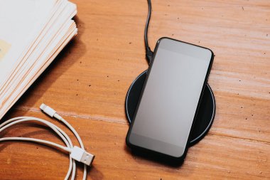 Akıllı telefonu masaüstünde kablosuz şarj cihazıyla şarj etmek.