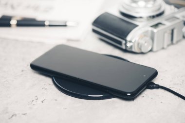 Akıllı telefonu masaüstünde kablosuz şarj cihazıyla şarj etmek.