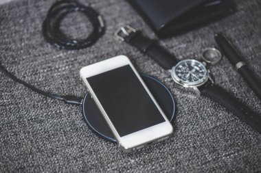 Akıllı telefonu gri kumaş üzerine kablosuz şarj cihazıyla şarj etmek.