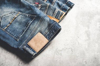 Beton arka planda bir sürü kot pantolon var. Erkekler kot pantolon giyer.