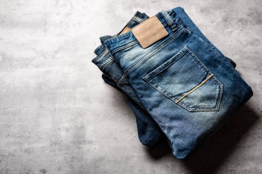 Beton arka planda bir sürü kot pantolon var. Erkekler kot pantolon giyer.