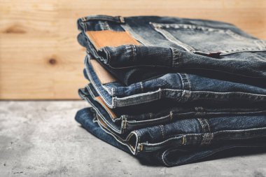Beton arka planda bir sürü kot pantolon var. Erkekler kot pantolon giyer.