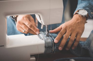Terzi kot pantolonla çalışıyor. Terzi kot pantolon giyiyor..