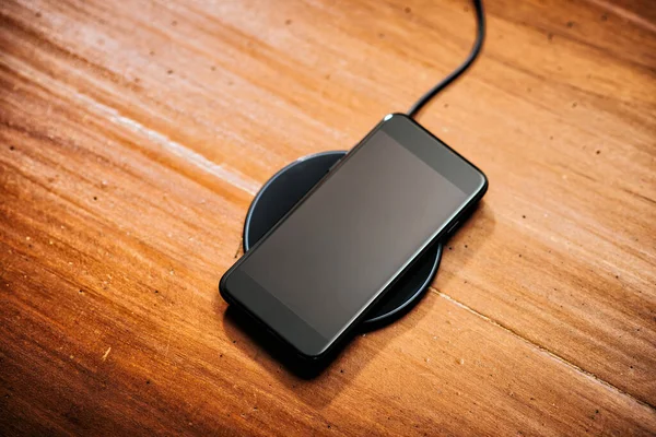 デスクトップ上のワイヤレス充電器でスマートフォンを充電 — ストック写真