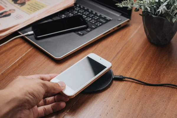 木製の机の上にワイヤレス充電器でスマートフォンを充電 — ストック写真