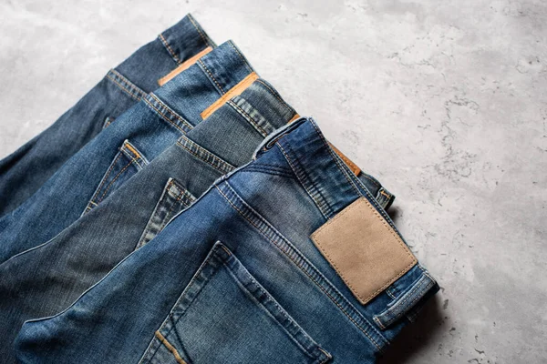 Veel Blauwe Jeans Een Betonnen Ondergrond Herenmode Denim Jeans — Stockfoto