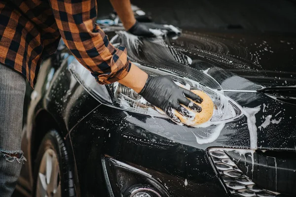 Washing the black car. Car cleaning and car care concept.