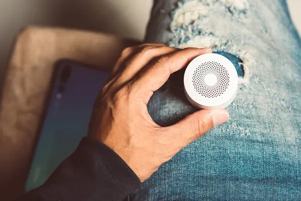 The man streams music from smartphone to bluetooth speaker.