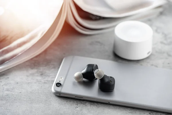 Pair of black true wireless earbuds with smartphone. Relaxation concept.