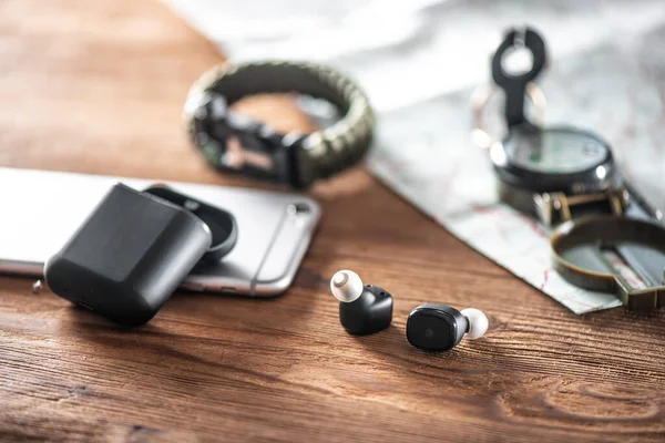 Pair of black true wireless earbuds with smartphone. Relaxation concept.