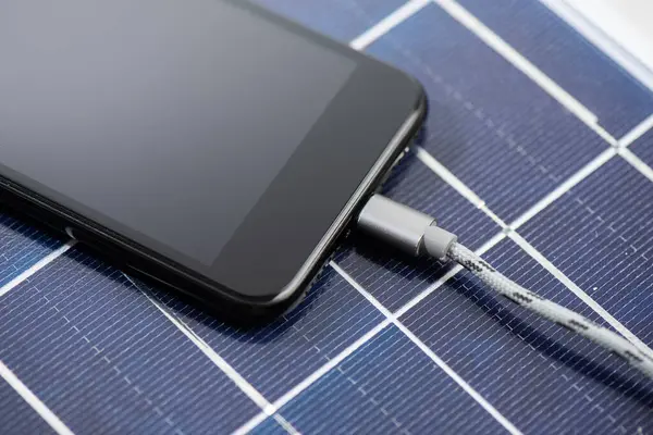 Laden Des Smartphones Mit Solarenergie Grünes Energiekonzept lizenzfreie Stockbilder