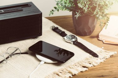 Akıllı telefonu ahşap masadaki kablosuz şarjla şarj etmek. Modern yaşam tarzı kavramı.