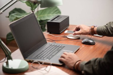 Akıllı telefonu ahşap masadaki kablosuz şarjla şarj etmek. Modern yaşam tarzı kavramı.