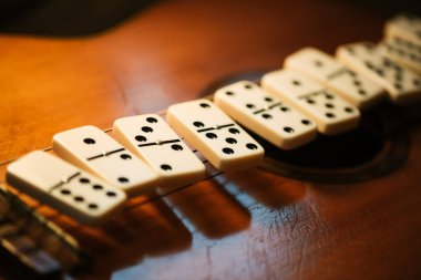 Domino taşlarını ve eski gitarı kapat. Domino en ünlü klasik oyunlardan biridir. Düşük ışık ve sığ alan derinliğinde çekim.