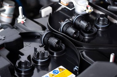 Makine dairesinde araba aküsünü kontrol ediyorum. Araba bakım konsepti.