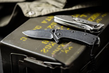 Paslanmaz çelik çakı ve arkasında askeri nesneler var..