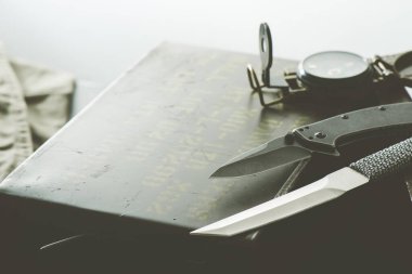 Paslanmaz çelik çakı ve arkasında askeri nesneler var..