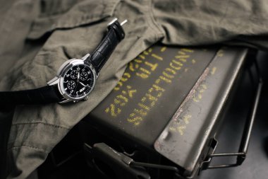 Siyah deri saat bandıyla askeri kol saatini kapat. Arka planda askeri nesneler olan erkekler için kol saati.