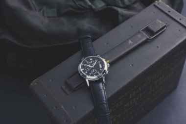 Siyah deri saat bandıyla askeri kol saatini kapat. Arka planda askeri nesneler olan erkekler için kol saati.