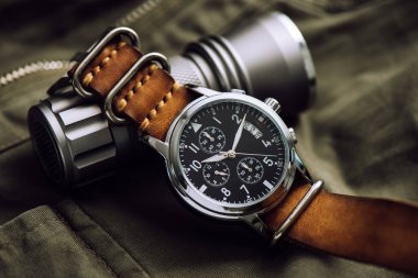 Deri saat bandıyla askeri kol saatini kapat. Arka planda askeri nesneler olan erkekler için kol saati.