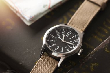 Biege naylon saat bandıyla askeri kol saatini kapat. Arka planda askeri nesneler olan erkekler için kol saati.